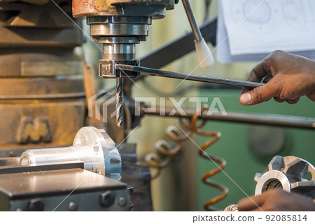 The machine operator use wrench tighten the spindle for change drill tool. The machine operator use wrench tighten the spindle for change drill tool. 92085814