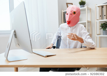 Focused funny crazy businesswoman worker freelancer in pink fish mask work on computer online pondering or making decision thinking of problem solution in light modern office. Copy space Focused funny crazy businesswoman worker freelancer in pink fish mask work on computer online pondering or making decision thinking of problem solution in light modern office. Copy space 92086302