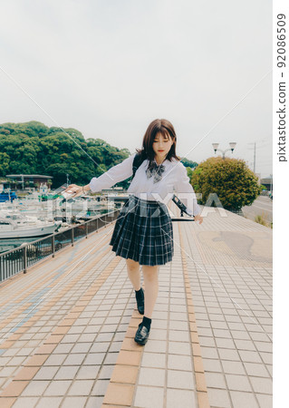 Schoolgirl in uniform and beautiful coastal scenery Schoolgirl in uniform and beautiful coastal scenery 92086509