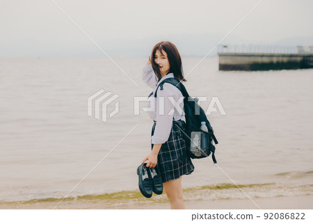 Schoolgirl in uniform and beautiful coastal scenery 92086822