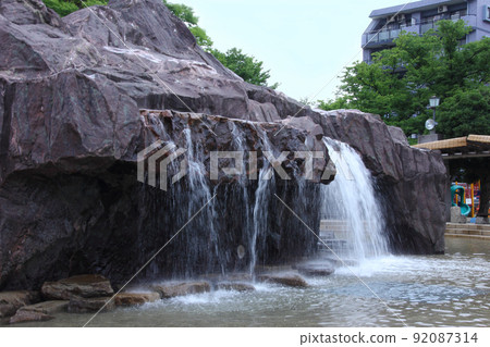 Waterfalls that flow vigorously into the jub-jub pond in the summer park are a favorite water playground for children. Waterfalls that flow vigorously into the jub-jub pond in the summer park are a favorite water playground for children. 92087314