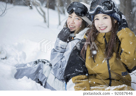 Snowboarding girls posing at a snowy ski resort 92087646