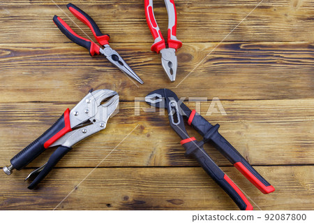 Set of different pliers on wooden background. Top view 92087800