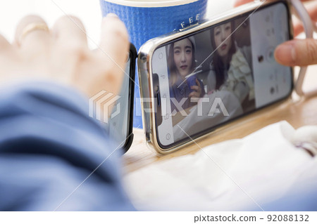 Two young women taking pictures in a ski resort cafe space going out 92088132