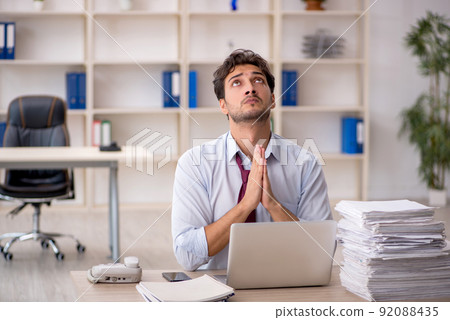 Young male employee and too much work in the office Young male employee and too much work in the office 92088435