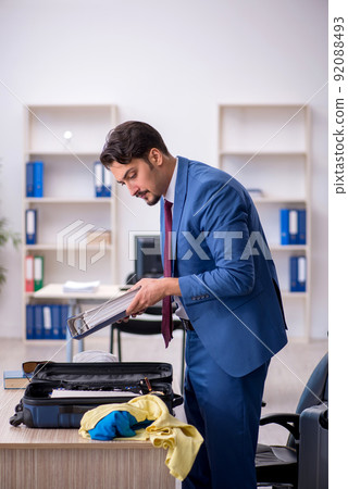 Young male employee preparing for trip at workplace 92088493