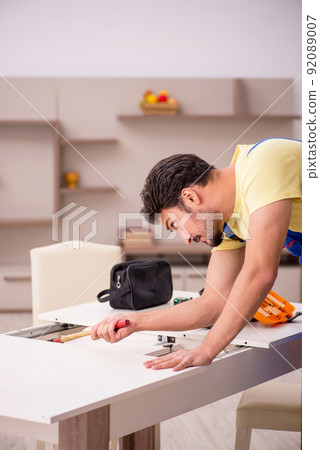 Young male carpenter repairing table at home 92089007
