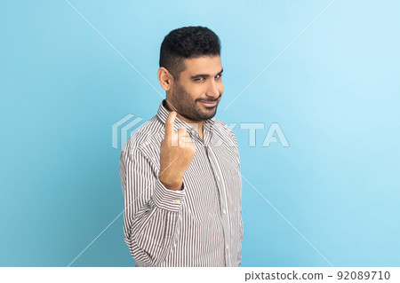 Portrait of serious bossy bearded businessman looking directly at camera with strict facial expression, come here, wearing striped shirt. Indoor studio shot isolated on blue background. 92089710