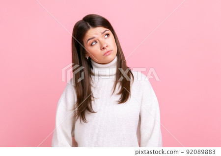 Confused puzzles female looking thoughtfully away with pensive expression, making decision, solving dilemma, wearing white casual style sweater. Indoor studio shot isolated on pink background. Confused puzzles female looking thoughtfully away with pensive expression, making decision, solving dilemma, wearing white casual style sweater. Indoor studio shot isolated on pink background. 92089883