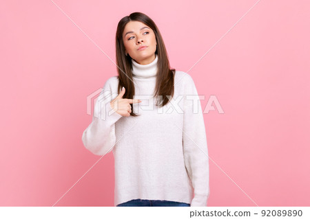 Portrait of confident female pointing at herself, feeling proud and self-important, having big ego, wearing white casual style sweater. Indoor studio shot isolated on pink background. Portrait of confident female pointing at herself, feeling proud and self-important, having big ego, wearing white casual style sweater. Indoor studio shot isolated on pink background. 92089890