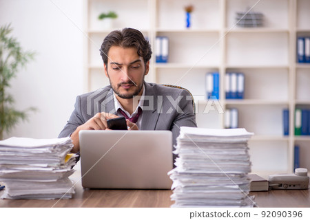 Young male employee and too much work in the office Young male employee and too much work in the office 92090396