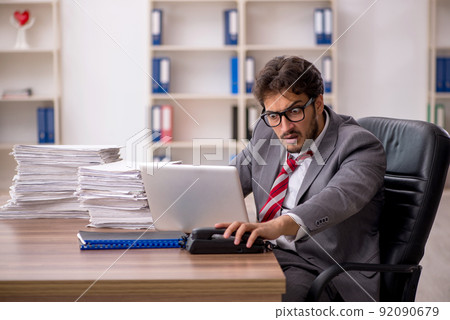Young male employee unhappy with excessive work in the office Young male employee unhappy with excessive work in the office 92090679