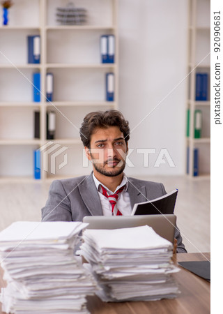 Young male employee unhappy with excessive work in the office Young male employee unhappy with excessive work in the office 92090681