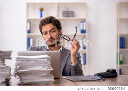 Young male employee unhappy with excessive work in the office Young male employee unhappy with excessive work in the office 92090684