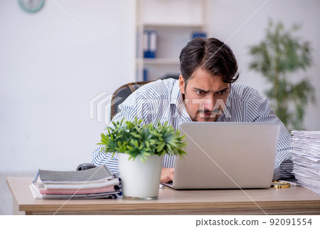 Young male employee unhappy with excessive work in the office 92091554