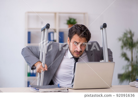 Young male employee after car accident working in the office Young male employee after car accident working in the office 92091636