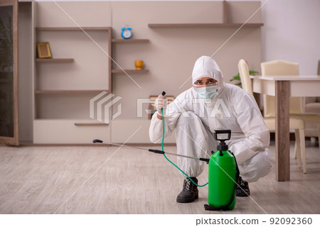 Young male contractor doing pest control at home 92092360