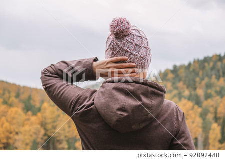 woman traveler stands on mountain and enjoys view of the autumn forest from above. rear view. 92092480