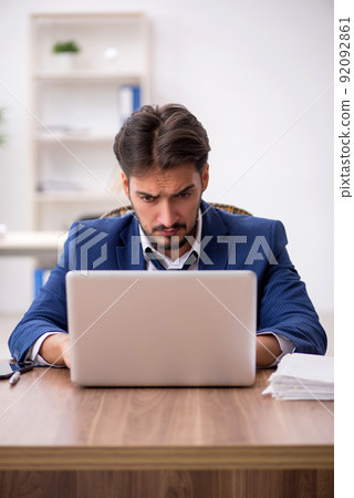 Young male employee unhappy with excessive work in the office Young male employee unhappy with excessive work in the office 92092861