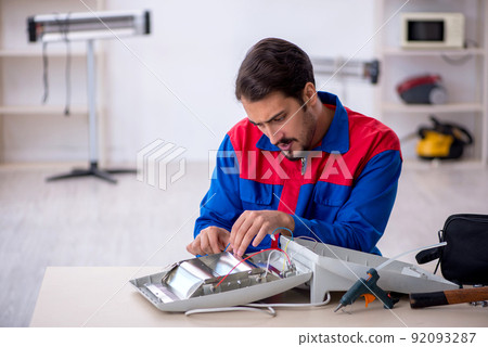 Young male repairman repairing heater 92093287