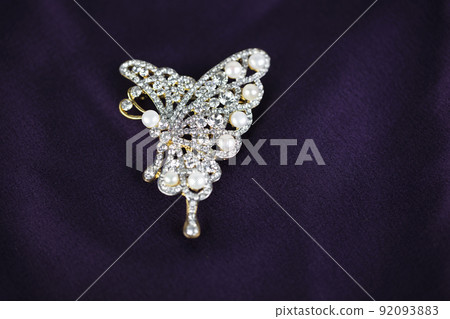 Pearl and diamond brooch in the shape of a butterfly isolated on a purple silk background 92093883