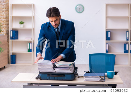 Young male employee preparing for business trip at workplace Young male employee preparing for business trip at workplace 92093982