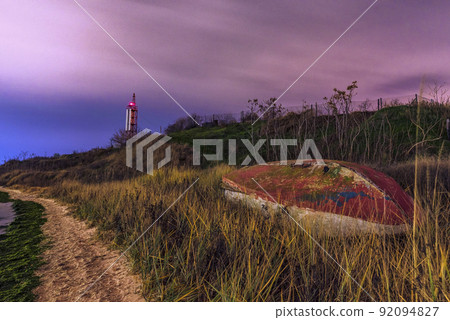 Boat on the beach at night. Lighthouse in the back. Beautiful landscape. 92094827