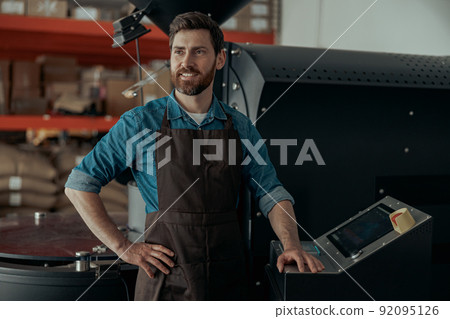 Business owner operating of coffee roasting machine on small roasted factory and looking away 92095126