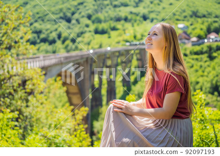 Montenegro. Woman tourist in background of Dzhurdzhevich Bridge Over The River Tara. Travel around Montenegro concept. Sights of Montenegro Montenegro. Woman tourist in background of Dzhurdzhevich Bridge Over The River Tara. Travel around Montenegro concept. Sights of Montenegro 92097193