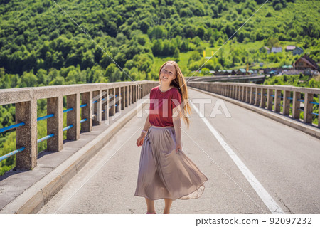 Montenegro. Woman tourist in background of Dzhurdzhevich Bridge Over The River Tara. Travel around Montenegro concept. Sights of Montenegro 92097232