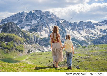 Family of tourists mom and son in Mountain lake landscape on Durmitor mountain in Montenegro beautiful Durmitor National park with lake glacier and reflecting mountain Family of tourists mom and son in Mountain lake landscape on Durmitor mountain in Montenegro beautiful Durmitor National park with lake glacier and reflecting mountain 92097253