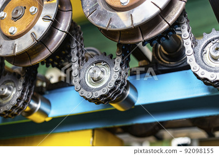 Rolls of an industrial machine for cutting metal with a chain transmission. Conveyor line in a factory for processing sheet steel. Close-up of production equipment. 92098155