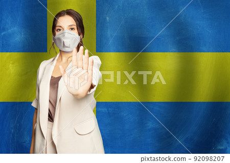 Portrait of serious young cute woman in protective mask showing stop gesture Portrait of serious young cute woman in protective mask showing stop gesture 92098207