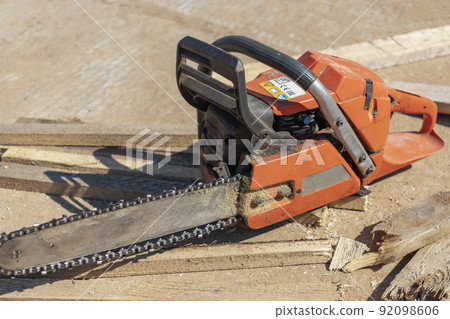 Chainsaw at the construction site. Reliable mobile tool for cutting boards and wooden blocks. 92098606