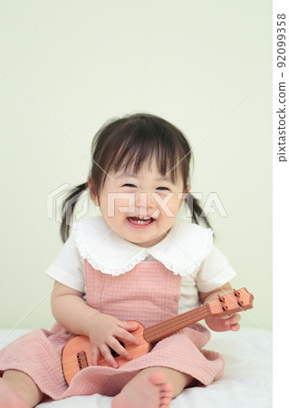 1 year old girl playing with guitar toys 92099358