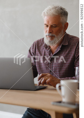 adult business man with gray hair is working at a laptop in his office. career finance and marketing, senior executive lawyer or financier in the company adult business man with gray hair is working at a laptop in his office. career finance and marketing, senior executive lawyer or financier in the company 92099812