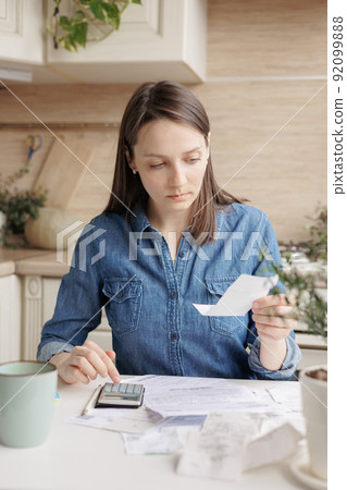 woman pays utility bills and writes checks. a European woman at home makes a calculation of expenses for a month 92099888