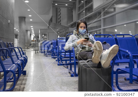 European woman at the airport waiting to board her flight, flight and boarding delays 92100347
