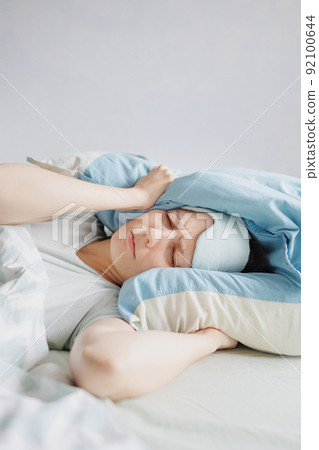 woman lies in bed and yawns or sleeps with a sleeping mask on her face. a European woman with sleep problems and insomnia 92100644