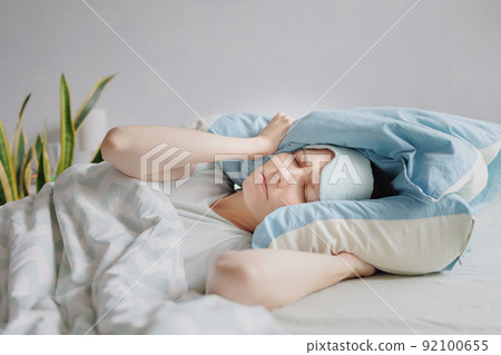 woman lies in bed and covers her head with pillows. the woman suffers from insomnia or sleep disorders woman lies in bed and covers her head with pillows. the woman suffers from insomnia or sleep disorders 92100655