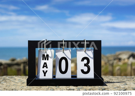 May 03 calendar date text on wooden frame with blurred background of ocean. May 03 calendar date text on wooden frame with blurred background of ocean. 92100975