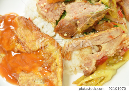 spicy stir fried barbecue pork neck with chili and basil leaf topping egg dressing sauce and rice on plate spicy stir fried barbecue pork neck with chili and basil leaf topping egg dressing sauce and rice on plate 92101070