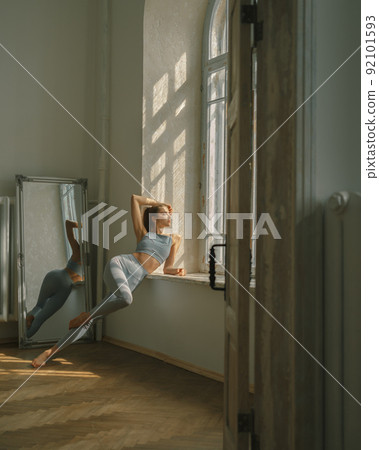 Fitness, yoga, stretching and healthy lifestyle concept - young woman doing exercises near window at home Fitness, yoga, stretching and healthy lifestyle concept - young woman doing exercises near window at home 92101593