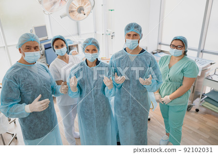 Team of surgeons in the operating room ready for surgery in clinic looking at camera 92102031