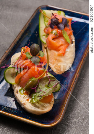bruschetta with salmon, cucumber and capers is a great snack. Close-up. Vertical photo. bruschetta with salmon, cucumber and capers is a great snack. Close-up. Vertical photo. 92103004