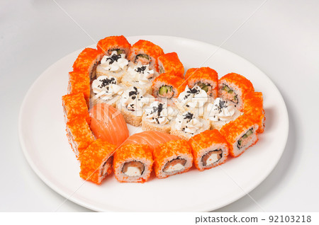 sushi rolls laid out in the shape of a heart on a white plate. Concept 92103218