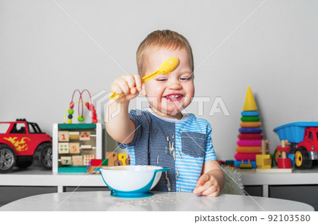 Toddler boy eats with spoon and is covered in food. Baby food, food allergies, self-feeding.... Toddler boy eats with spoon and is covered in food. Baby food, food allergies, self-feeding.... 92103580