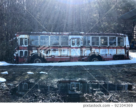 Abandoned bus in the snow illuminated by the morning sun 92104369