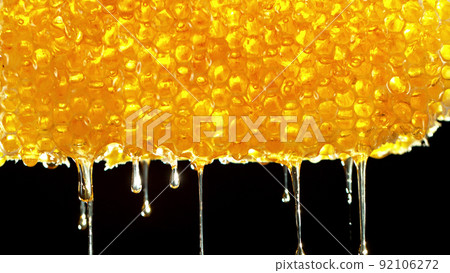 Honey dripping from honey comb on black background. Honey dripping from honey comb on black background. 92106272