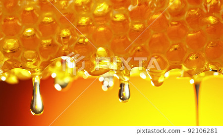 Honey dripping from honey comb on golden background. 92106281